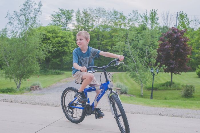 Young boy riding a bike outdoors, enjoying childhood joys before smartphones changed how memories are recorded.