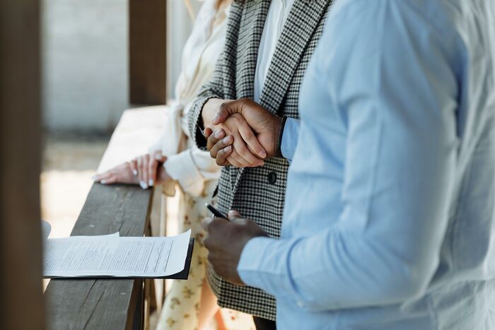Two professionals shaking hands outdoors near documents, illustrating dark truths of human behavior in a business setting.