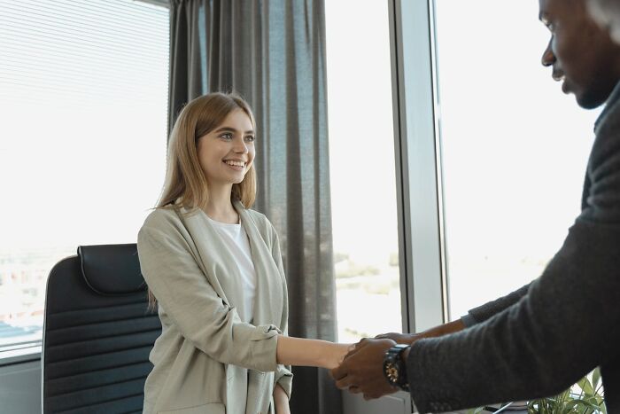 Private resort worker smiling and shaking hands with a man in an office setting during an informal meeting.