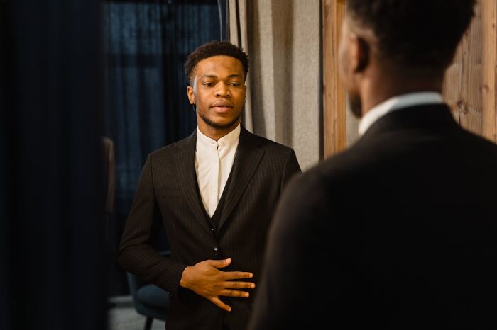 Private resort worker in a suit looking at his reflection while preparing for an ask me anything session.