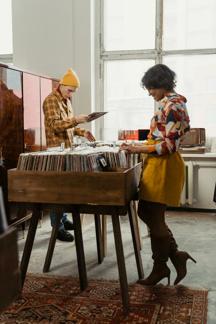 Two people browsing vinyl records in a vintage shop, capturing unique childhood joys not recorded with smartphones.