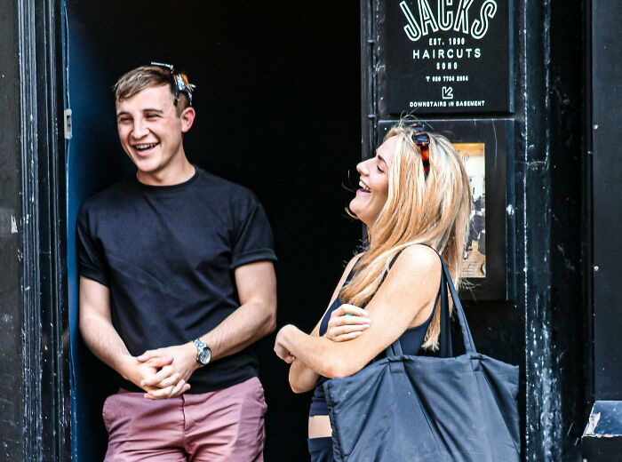 Two people laughing and chatting outside a UK barbershop, reflecting honest opinions about the UK culture.