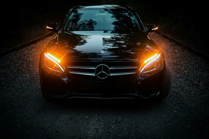 Black Mercedes-Benz with headlights and turn signals on, parked on a dark road, illustrating a completely normal thing.