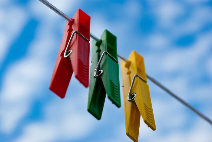 Red, green, and yellow clothespins hanging on a wire against a blue sky, illustrating weird things couples started doing.