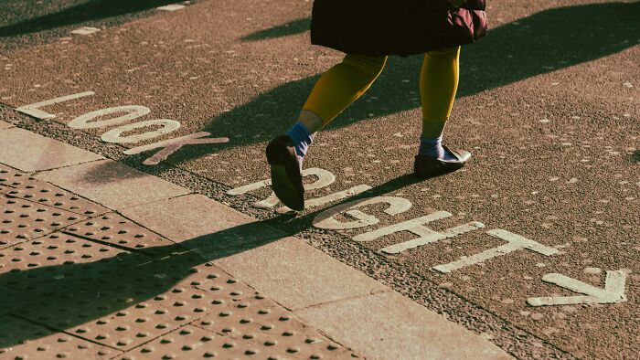 Person walking on a street with painted words and arrow, illustrating a completely normal thing causing irrational ick feelings.