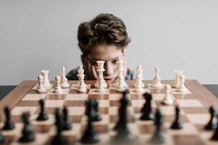 Young boy concentrating on chess game, deep in thought during a memorable I was there when it was written moment.
