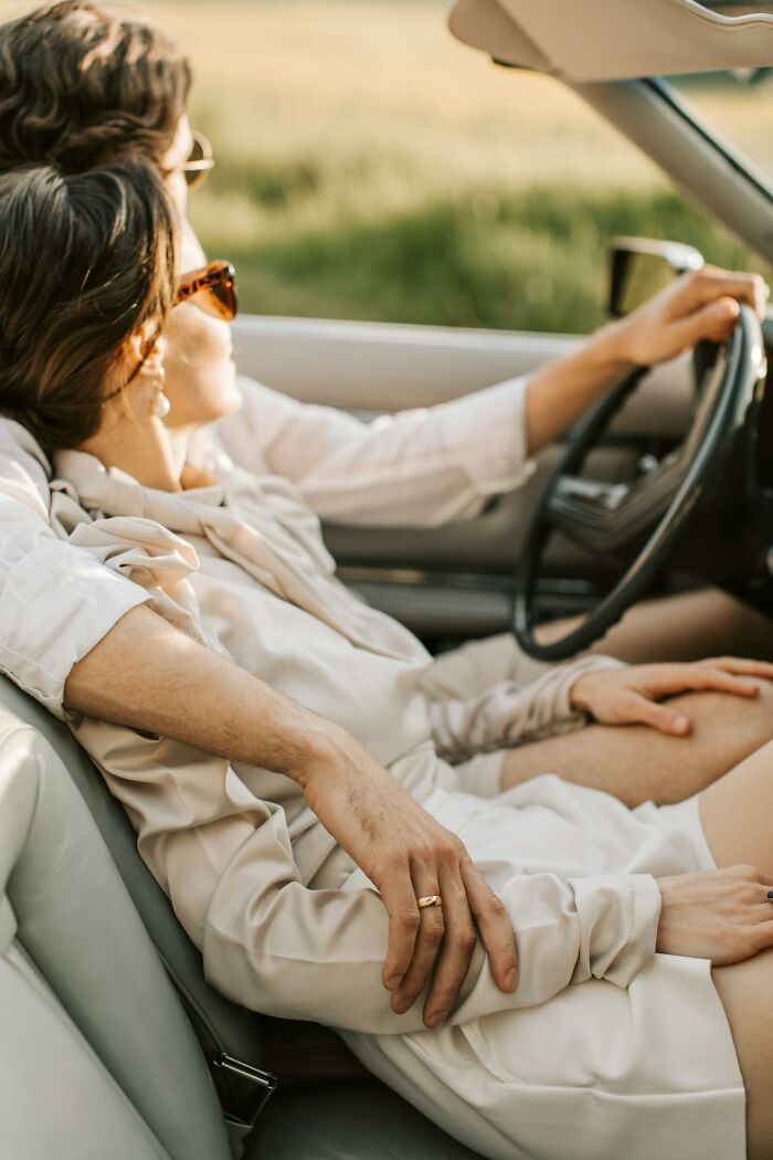 Couple sitting closely in a car with the man’s arm around the woman, highlighting women sharing wildest things with exes.