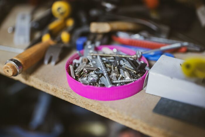 Close-up of a cluttered workbench showing screws and tools, reflecting poor people habits in tool organization.