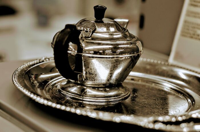 Vintage silver teapot on an ornate serving tray representing industries that took a huge hit from millennials.