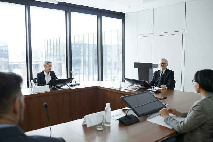Four business professionals in a modern conference room discussing company knowledge and expertise during a meeting.