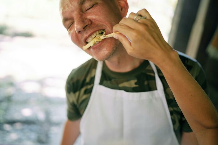 Man in white apron enjoying food outside, illustrating a completely normal thing causing an irrational ick feeling.