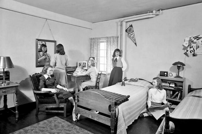 Black and white photo of girls in a vintage dorm room, capturing a timeless moment from the past showing what life looked like.