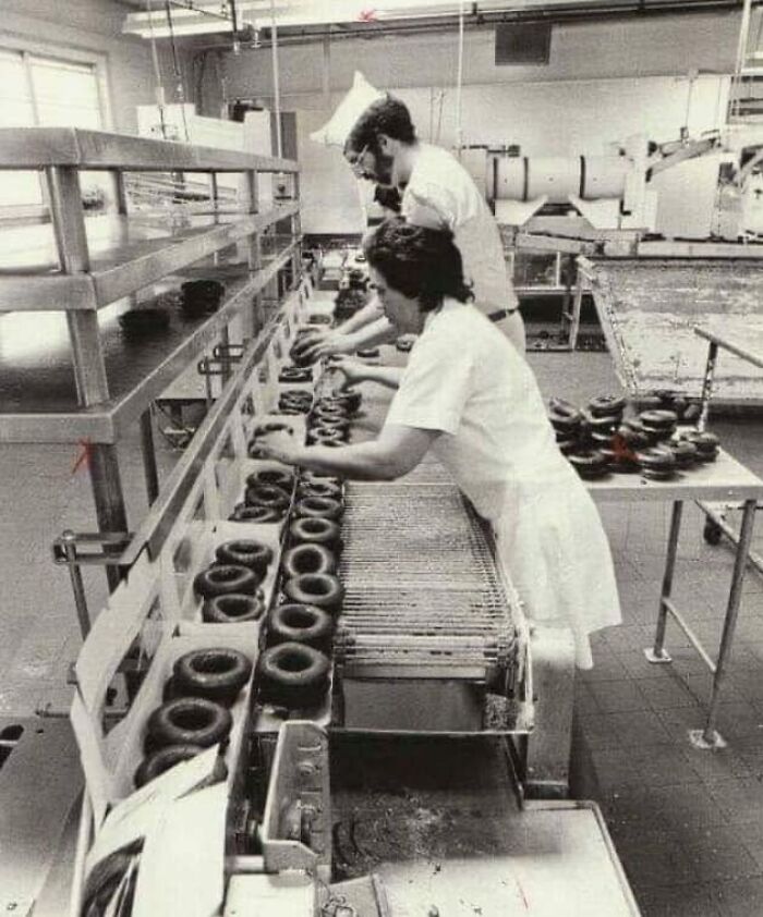 Workers assembling donuts on a production line in a factory, showcasing timeless photos that reveal what the past looked like.