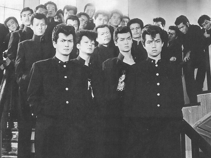 Group of young men in traditional school uniforms posed on stairs in a timeless photo showing what the past looked like.