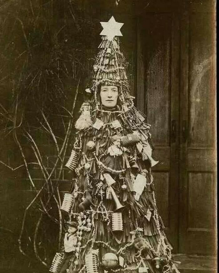 Vintage photo of a person dressed as a Christmas tree with ornaments and decorations showing the past in timeless photos.