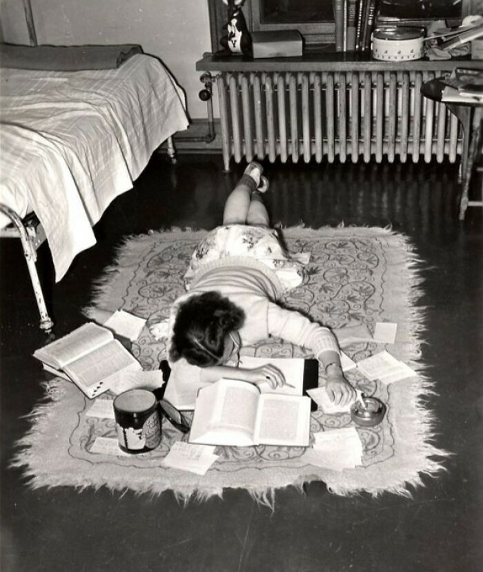 Niña estudiando sobre una alfombra en una habitación antigua, imagen histórica que muestra un lado distinto de la Historia.