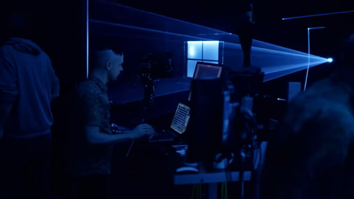 Person working on computer in dark room with multiple screens and lighting equipment, showcasing unseen alternative angles photos.