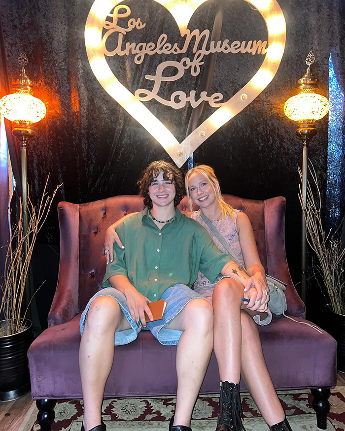 Couple sitting on a purple sofa at Los Angeles Museum of Love, related to Pitch Perfect star defending 18-year age gap.