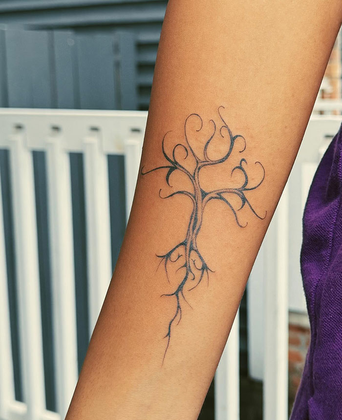 Minimalist poison tree tattoo with thin black lines and twisting branches on the inner forearm of a person. Minimalist poison tree tattoo with thin black lines and twisting branches on the inner forearm of a person.