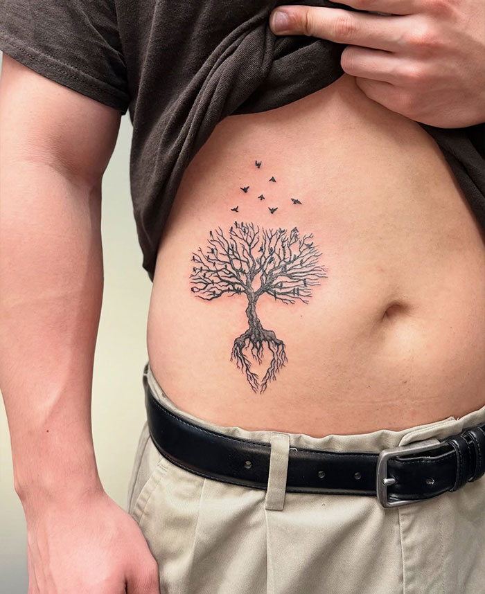 Minimalist poison tree tattoo with birds above, inked on a person's rib area as visual guide to poison tree tattoos. Minimalist poison tree tattoo with birds above, inked on a person's rib area as visual guide to poison tree tattoos.