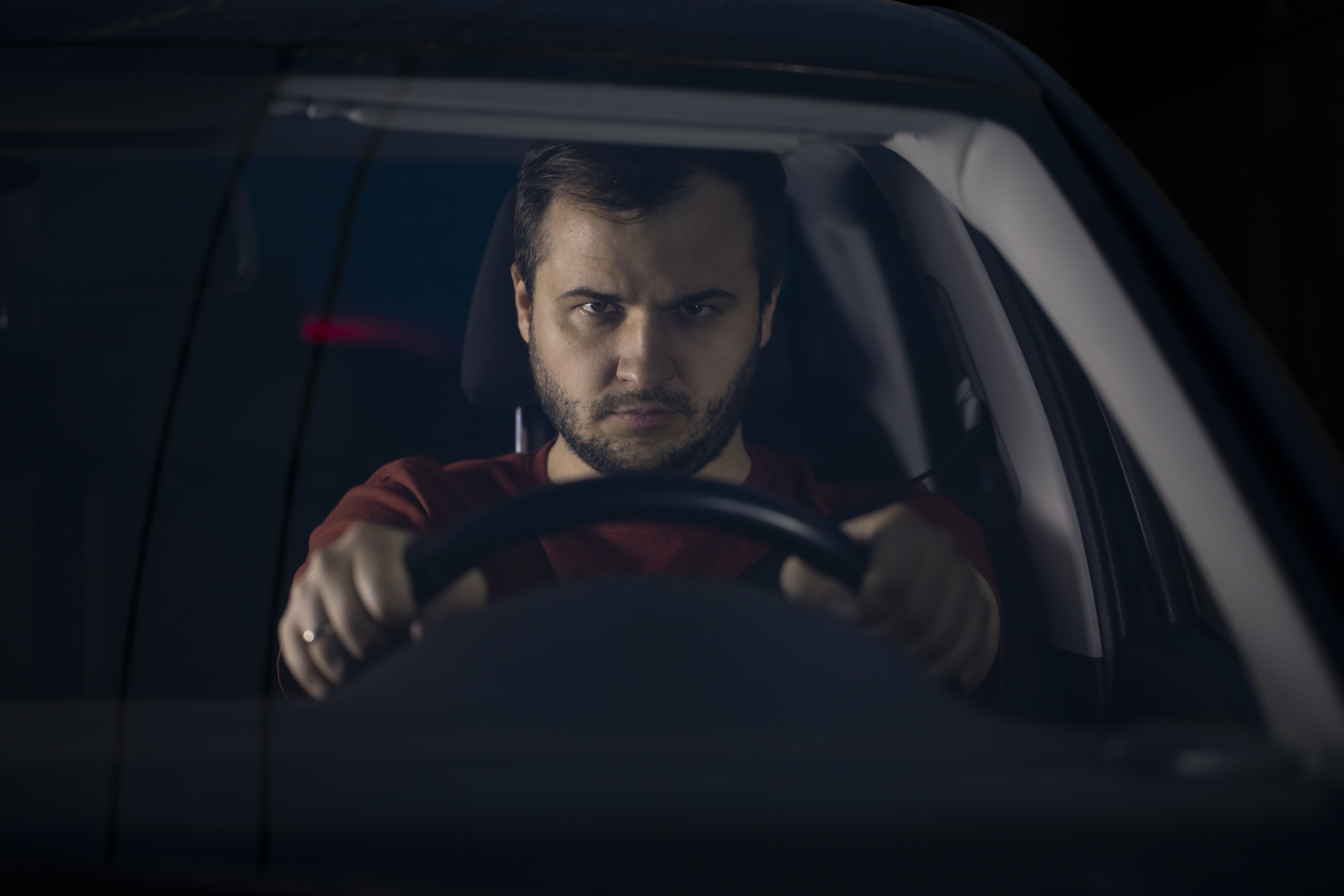Man focused on safe driving, gripping steering wheel inside car at night, demonstrating safe driving facts.