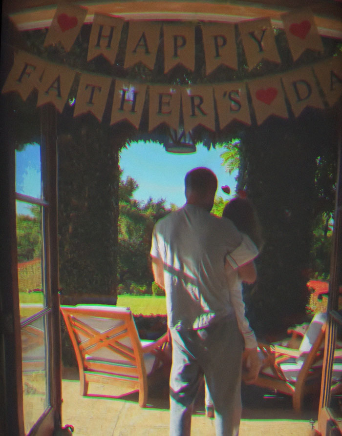 Man carrying child under a Happy Father’s Day banner, related to Meghan Markle's Father's Day post controversy. Man carrying child under a Happy Father’s Day banner, related to Meghan Markle's Father's Day post controversy.