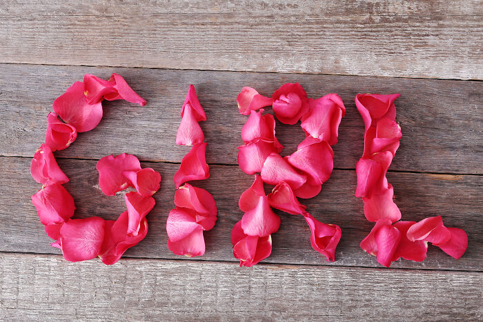 The word girl spelled out with pink rose petals on a wooden background, illustrating rich kid meltdowns.