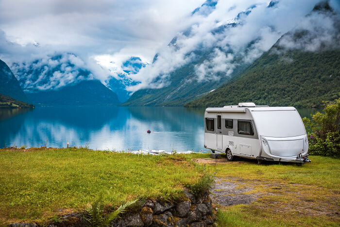 A campervan parked by a serene lake surrounded by mountains reflecting rich kid meltdowns at private schools.