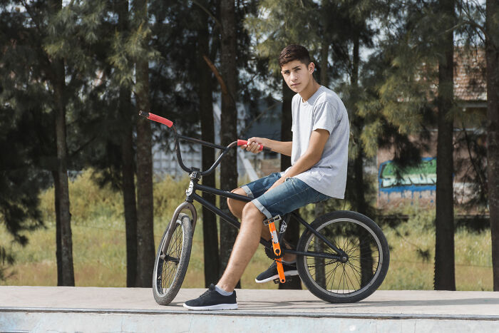 Teen boy in casual clothes sitting on BMX bike outdoors, illustrating rich kid meltdowns at private schools.