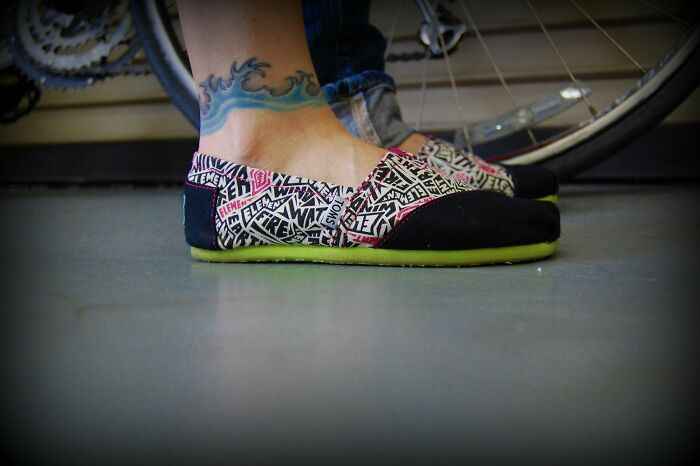 Close-up of feet in patterned slip-on shoes beside a bicycle, illustrating rich kid meltdowns at private schools.