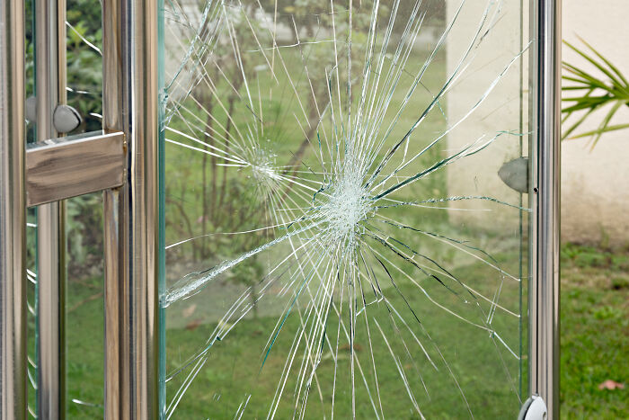 Broken glass door with shattered cracks, illustrating dramatic rich kid meltdowns at private schools.