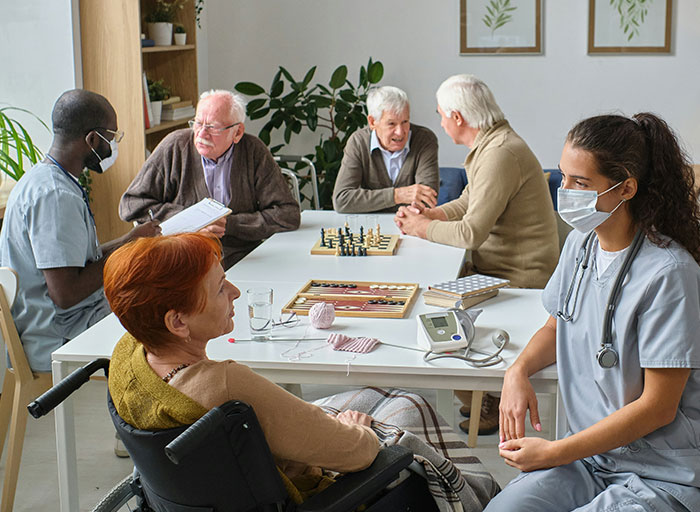Psychologists and elderly patients in a group therapy session wearing masks, engaging in conversation and activities.