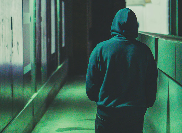 Person in a dark hoodie walking down a dimly lit corridor representing psychologists’ patients who scared them.