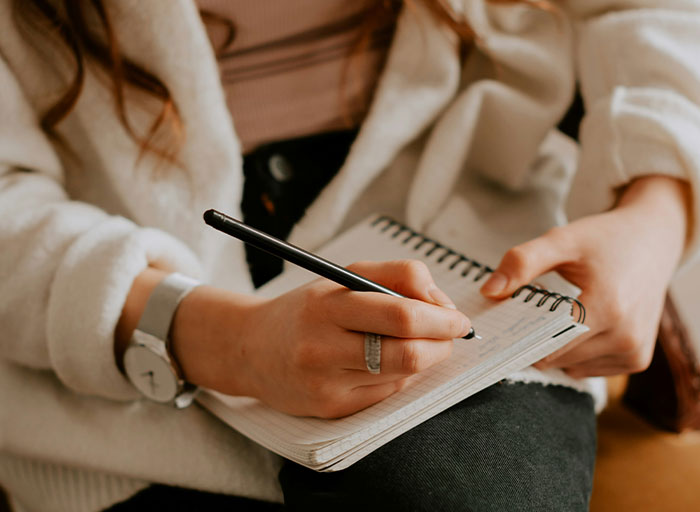 Close-up of a psychologist’s hands writing notes in a spiral notebook during a therapy session about patients who scared them.