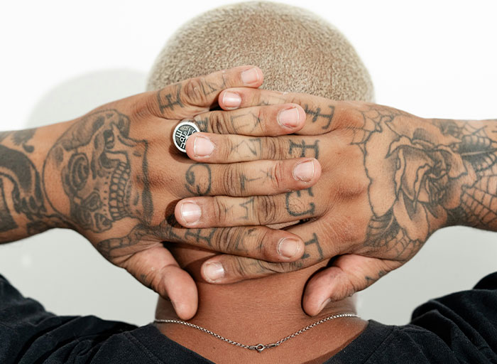 Person with tattooed hands covering the back of their head, symbolizing fear and insights from psychologists about patients.