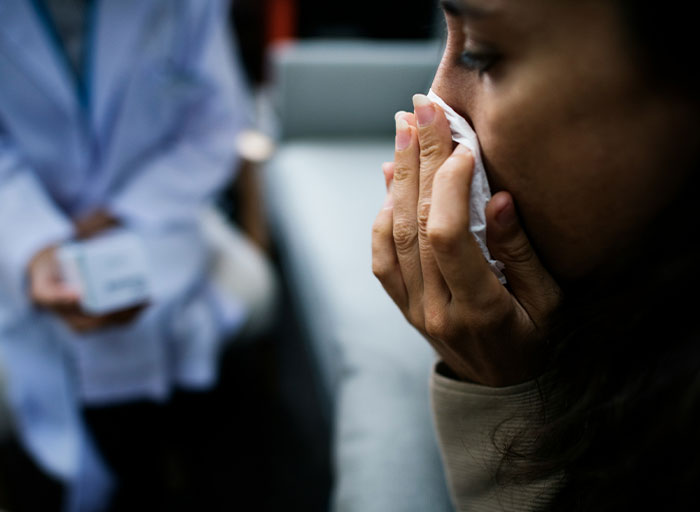 Patient visibly distressed, holding tissue while psychologist listens attentively during a therapy session.