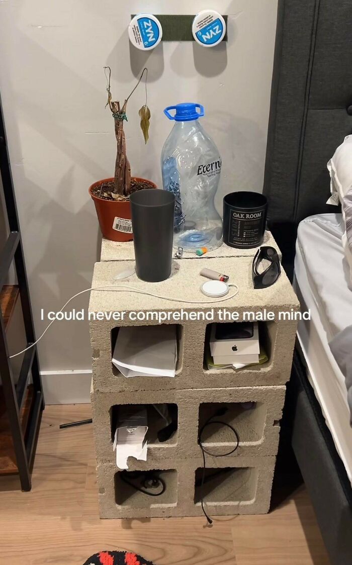 Nightstand made from cinder blocks holding random items with a humorous caption about the male mind in a bedroom setting.