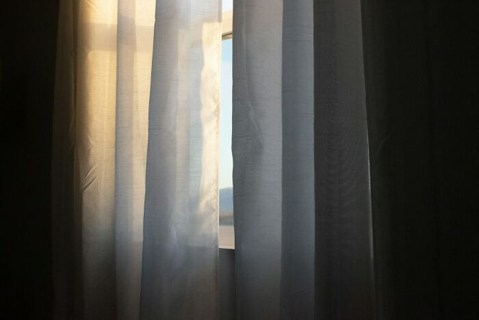 Sheer curtains partially open with sunlight filtering through, showcasing everyday items improving lives under $300.