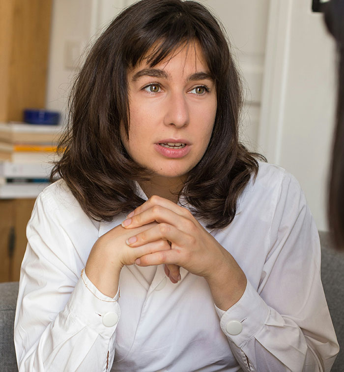 Woman with long dark hair wearing a white shirt, discussing refusing to cut hair for boyfriend&rsquo;s mom party.