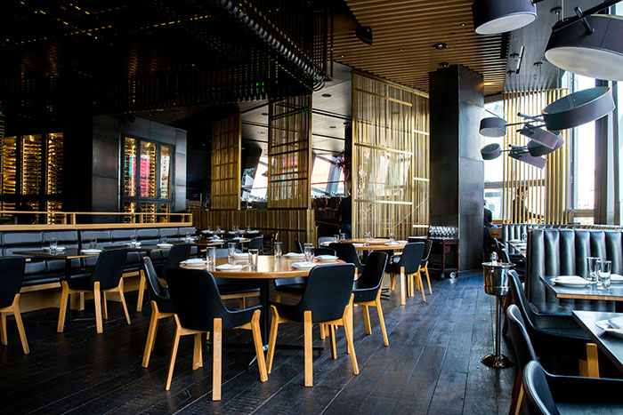 Empty modern restaurant interior with wooden tables and black chairs, emphasizing a stylish and wild design atmosphere.