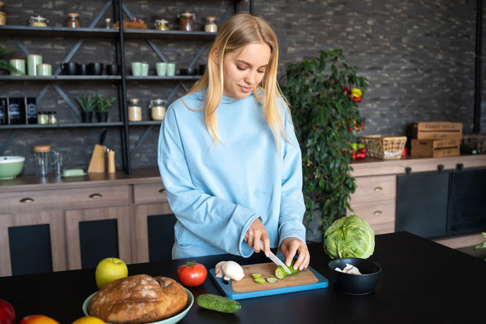 Young woman refusing to eat vegan meal preparing vegetables in kitchen on girlfriend birthday celebration. Young woman refusing to eat vegan meal preparing vegetables in kitchen on girlfriend birthday celebration.