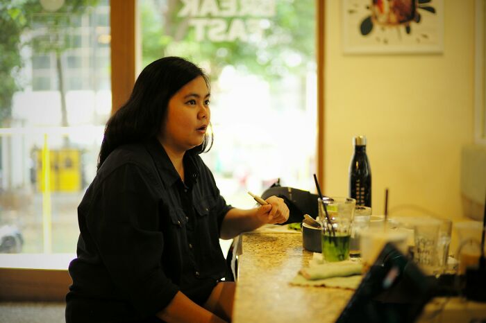 Woman sitting at a café counter, holding a pencil, reflecting on moments that drove away potential life partners.