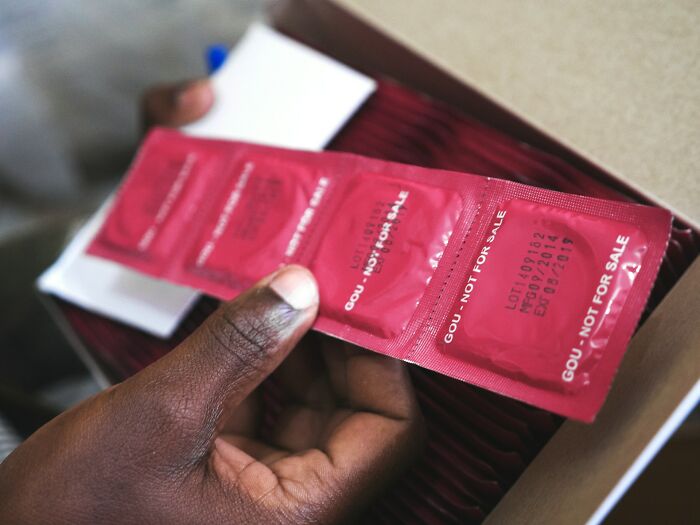 Hand holding a strip of condoms symbolizing challenges in modern dating and the importance of safe practices.