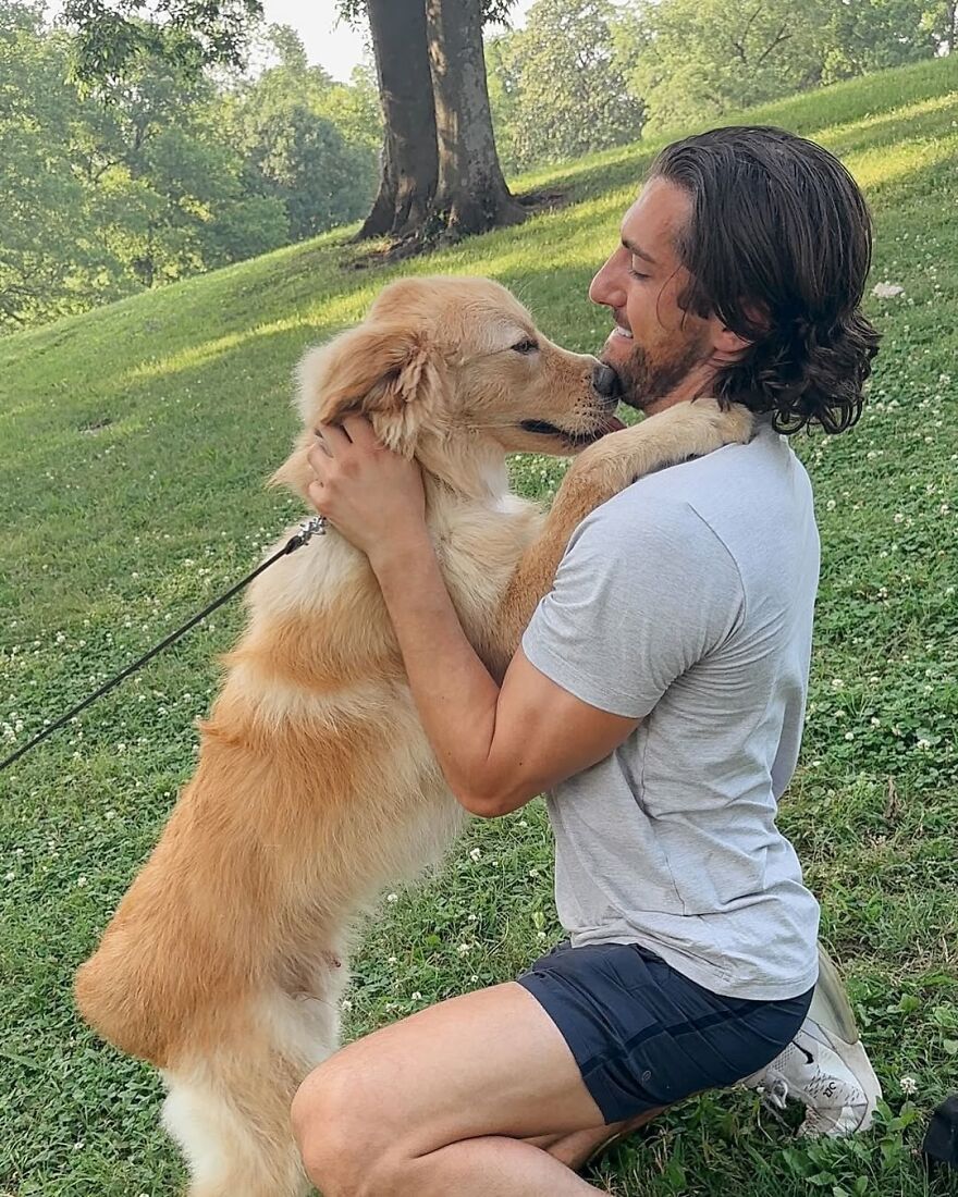 Rescue dog warmly reuniting with its owner outdoors, showing a joyful and loving embrace in a green park setting.