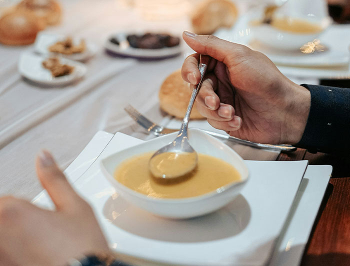 Person holding a spoon over a bowl of soup at a chain restaurant, highlighting items employees warn against ordering.