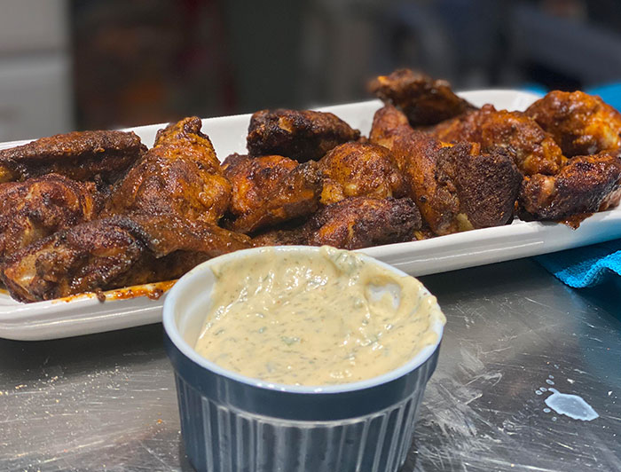 Plate of spicy chicken wings with dipping sauce, highlighting chain restaurant employees' warnings about unsafe orders.