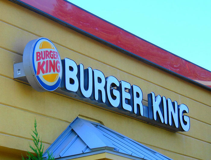 Burger King restaurant exterior sign with logo, related to chain restaurant employees and menu warnings.