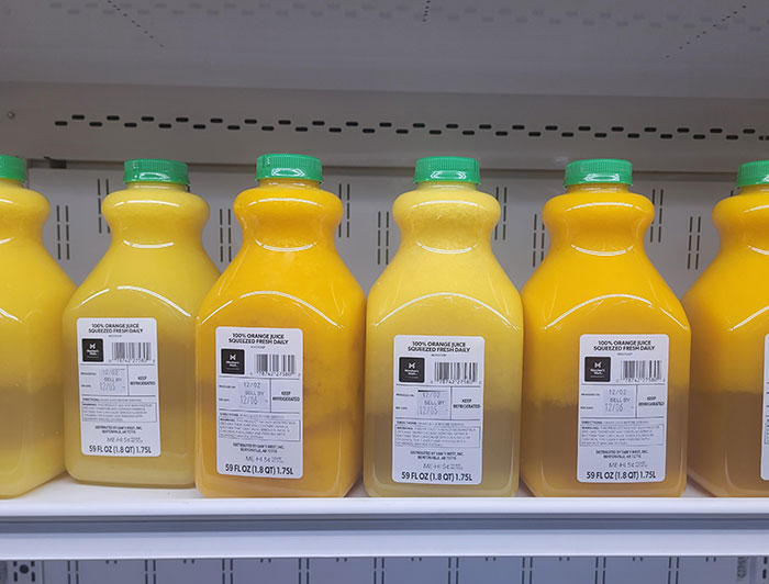 Bottles of orange juice on a grocery shelf, illustrating chain restaurant employees’ warnings about items to avoid ordering.