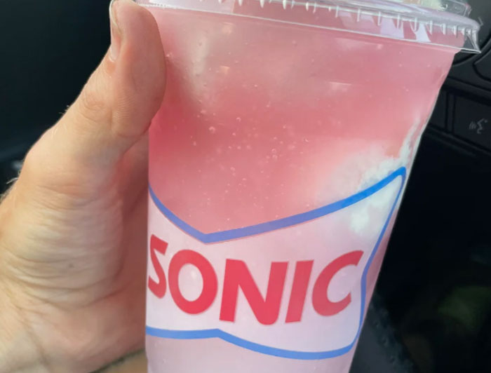 Hand holding a pink frozen drink from Sonic, highlighting chain restaurant employees warning about things to avoid ordering.