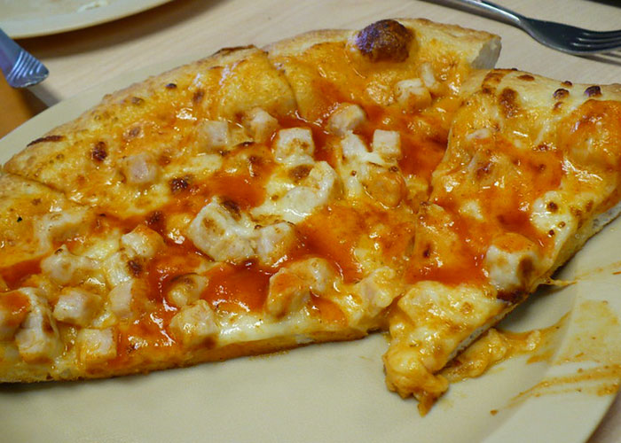 Buffalo chicken pizza slices on a plate, illustrating chain restaurant employees warnings on items to never order.
